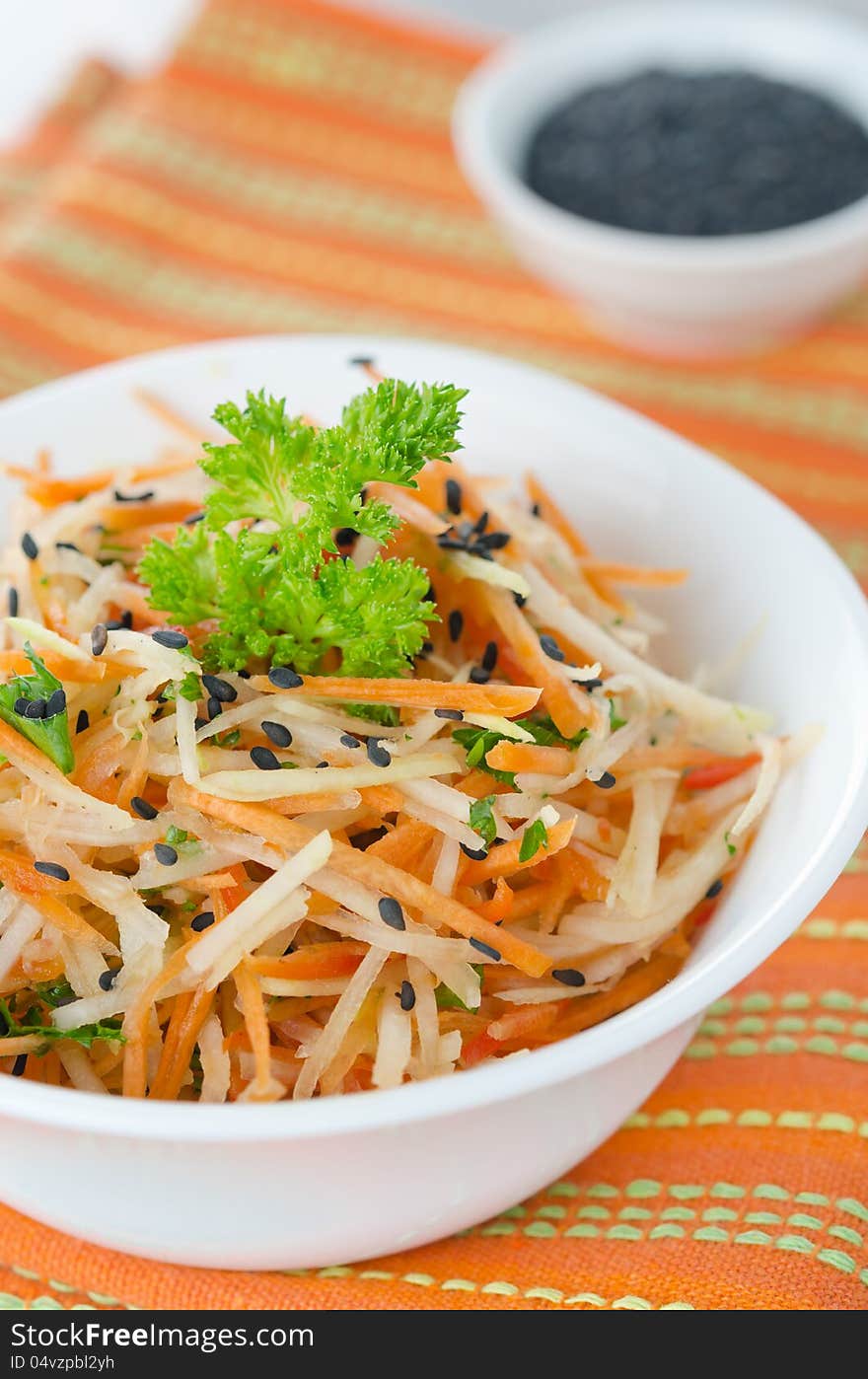 A bowl of salad with cauliflower, carrots and peppers, sprinkled with black sesame. A bowl of salad with cauliflower, carrots and peppers, sprinkled with black sesame