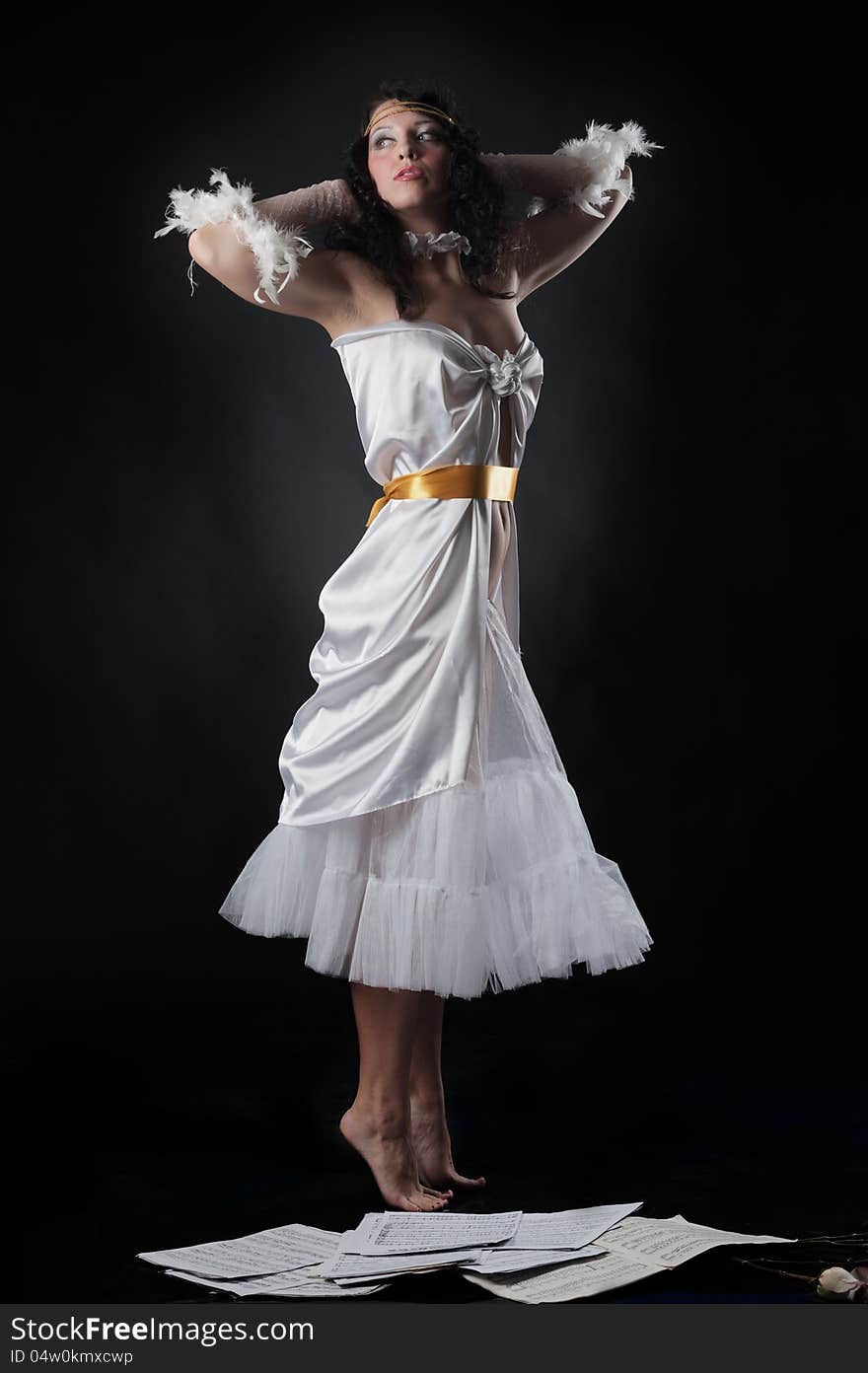 Portrait of a pretty girl in a white dress as if hovering over the notes on a black background in the studio. Portrait of a pretty girl in a white dress as if hovering over the notes on a black background in the studio