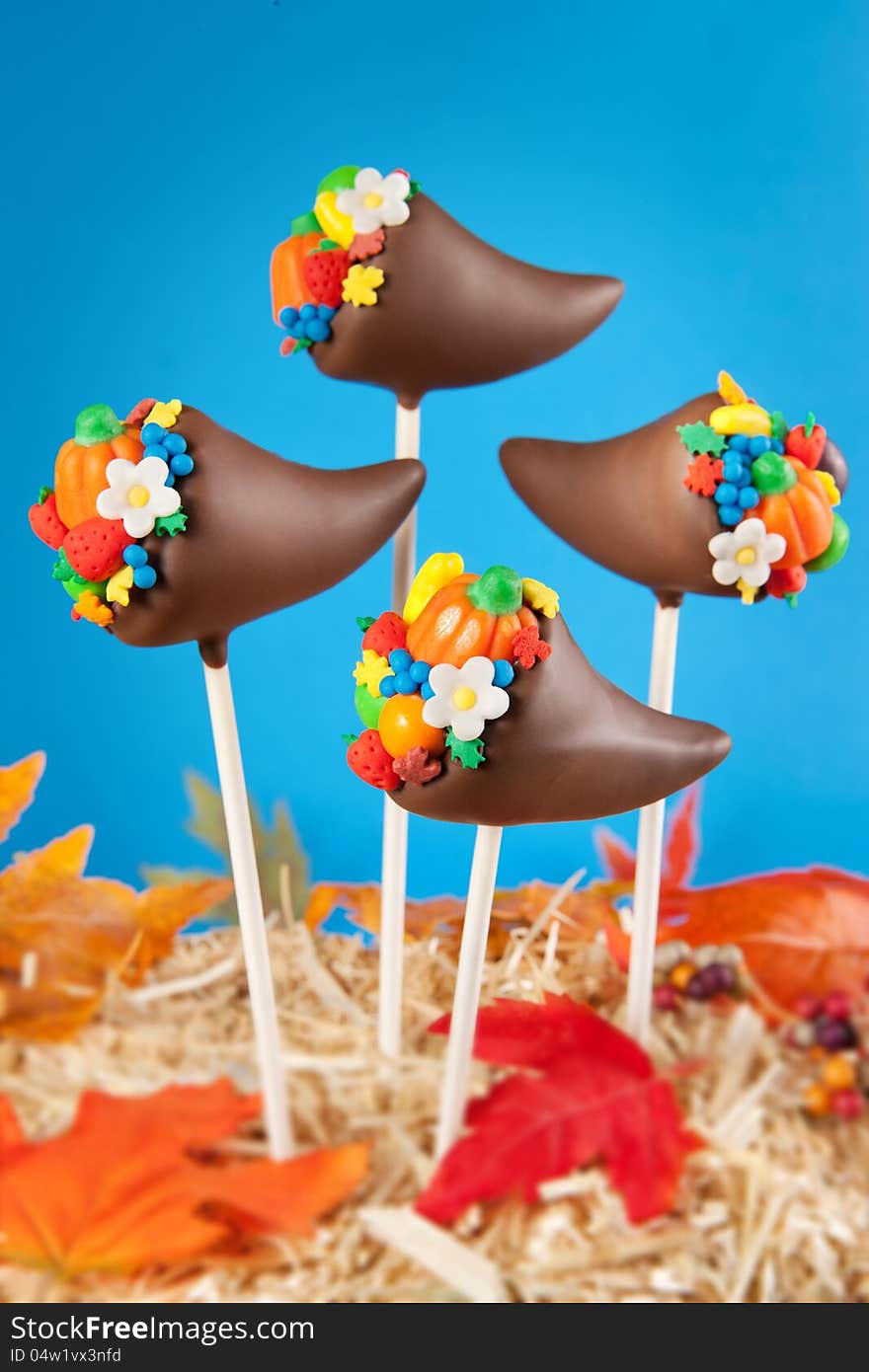 Thanksgiving cake pops. Mini cakes shaped like cornucopias, dipped in chocolate and decorated with candy, sprinkles, fondant fruits and flowers. Thanksgiving cake pops. Mini cakes shaped like cornucopias, dipped in chocolate and decorated with candy, sprinkles, fondant fruits and flowers