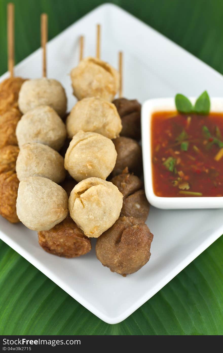 Fried meatballs skewers with sauce put on white dish