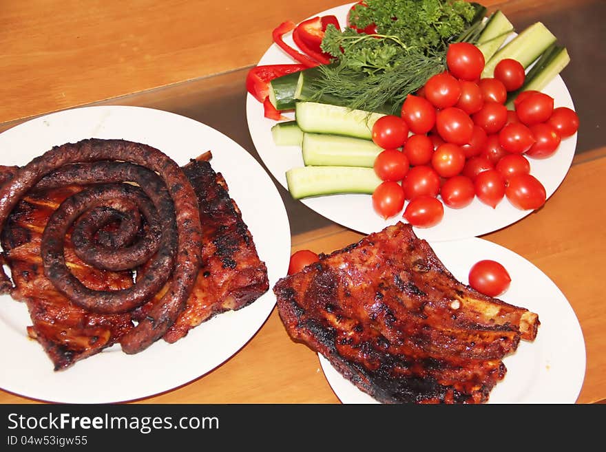 Grilled ribs and sausages with vegetables on the table