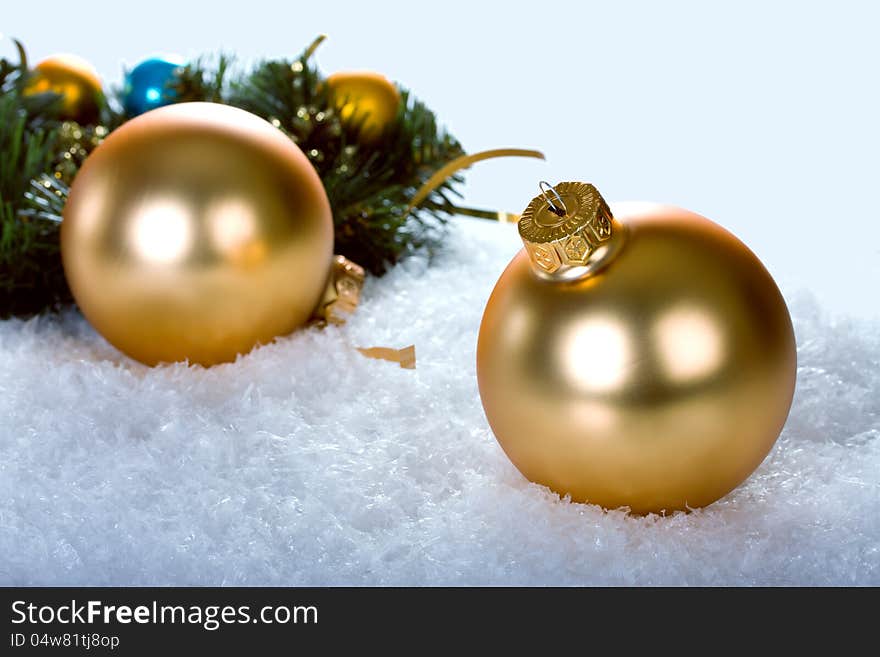 Golden christmas balls with branch christmas tree on blue snow