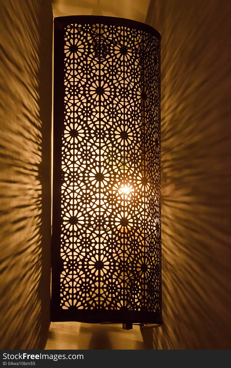 Ornate metal lamp glowing on wall. Ornate metal lamp glowing on wall