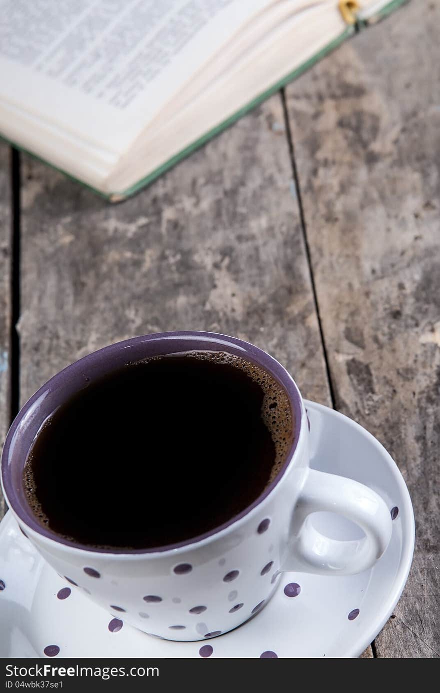 Cup of coffee and book on a wooden table. Cup of coffee and book on a wooden table