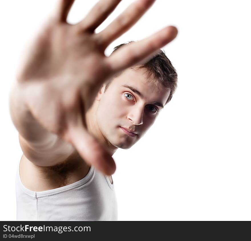 Portrait of a young man looking out from under raised hand on a light background