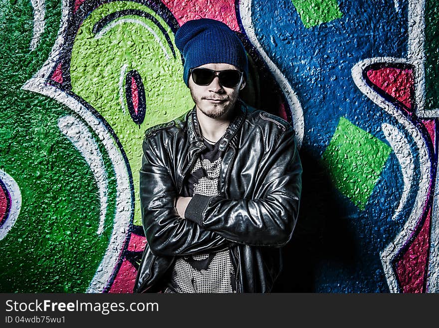 Fashion photo of young guy posing on bright wall