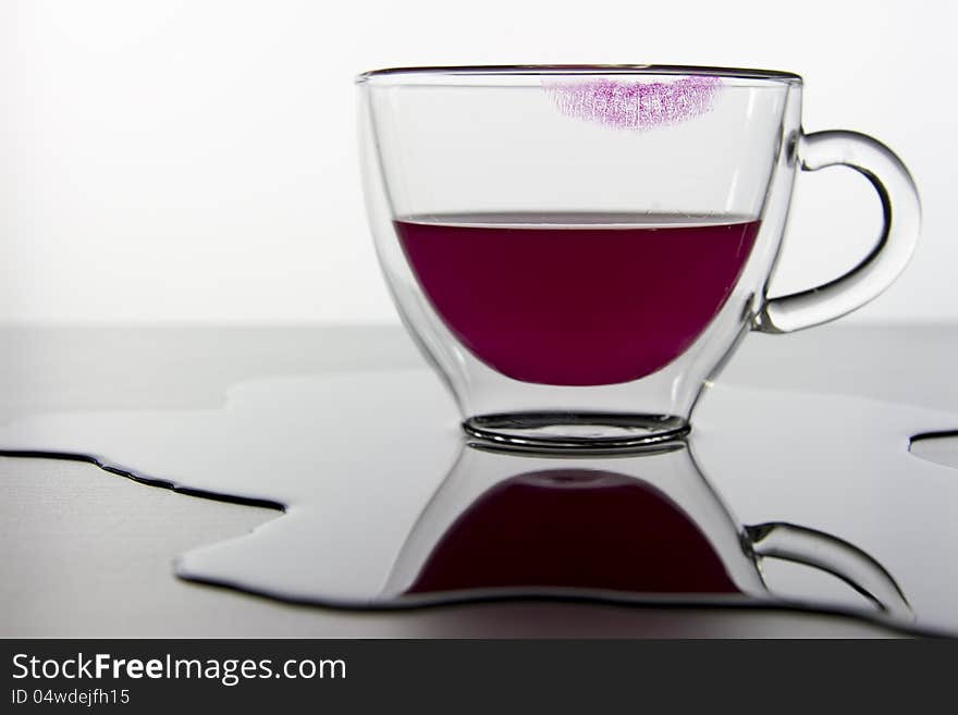 Empty glass and lipstick print and red liquid isolated on white background