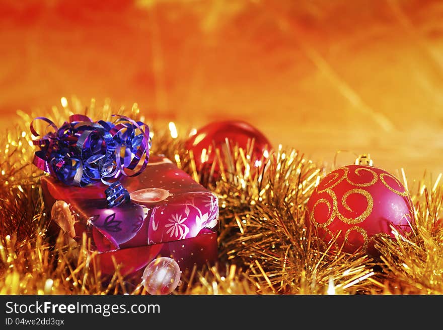 Christmas present and baubles against a blurred gold background. Christmas present and baubles against a blurred gold background