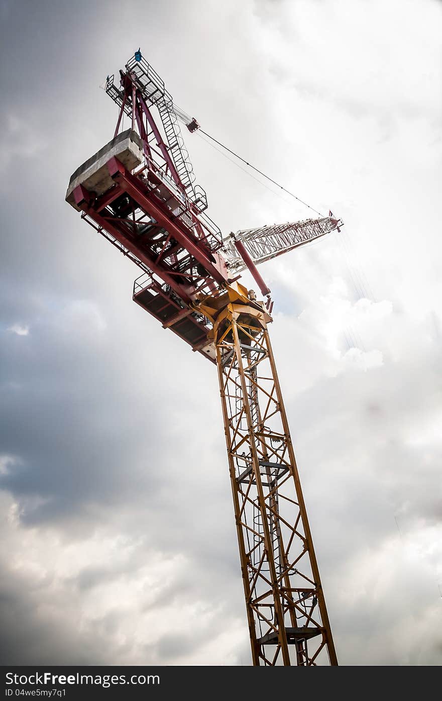 Yellow tower crane on building top with blue sky