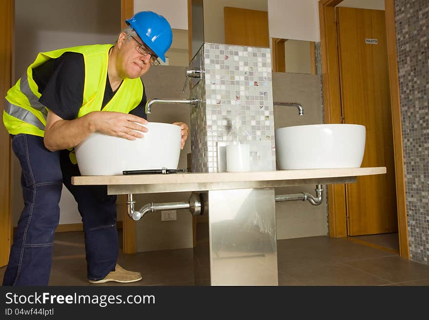 Plumber at work with a basing in a bathroom