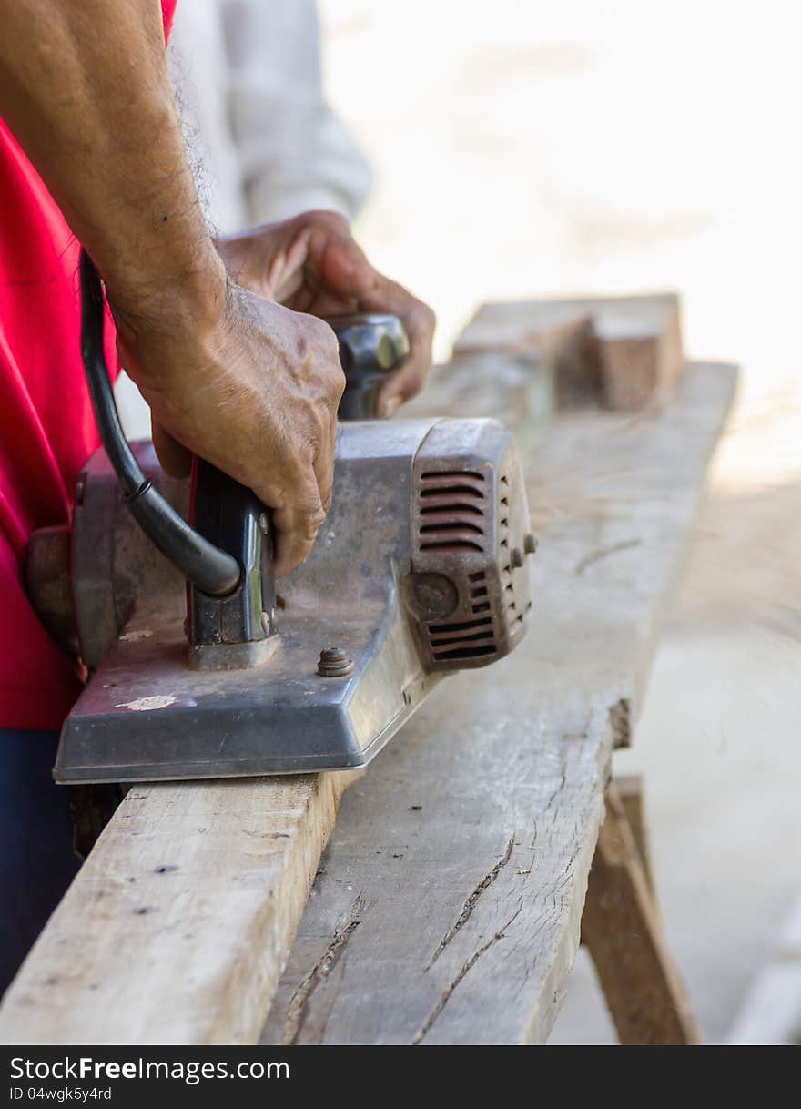 Carpenter working with electric planer in his workshop, close up on the tool with hands