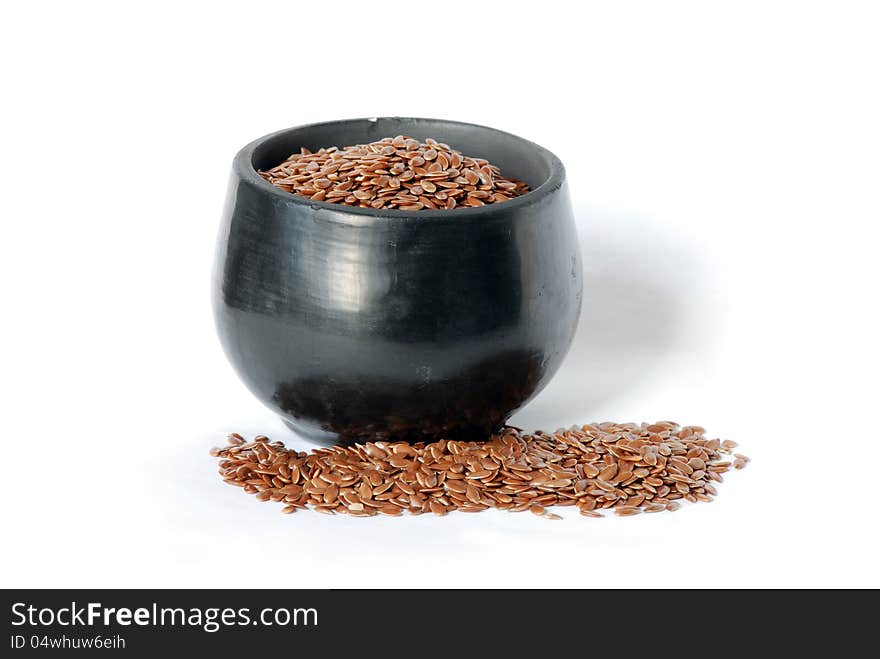 Flaxseed and a black ceramic cup on a white background