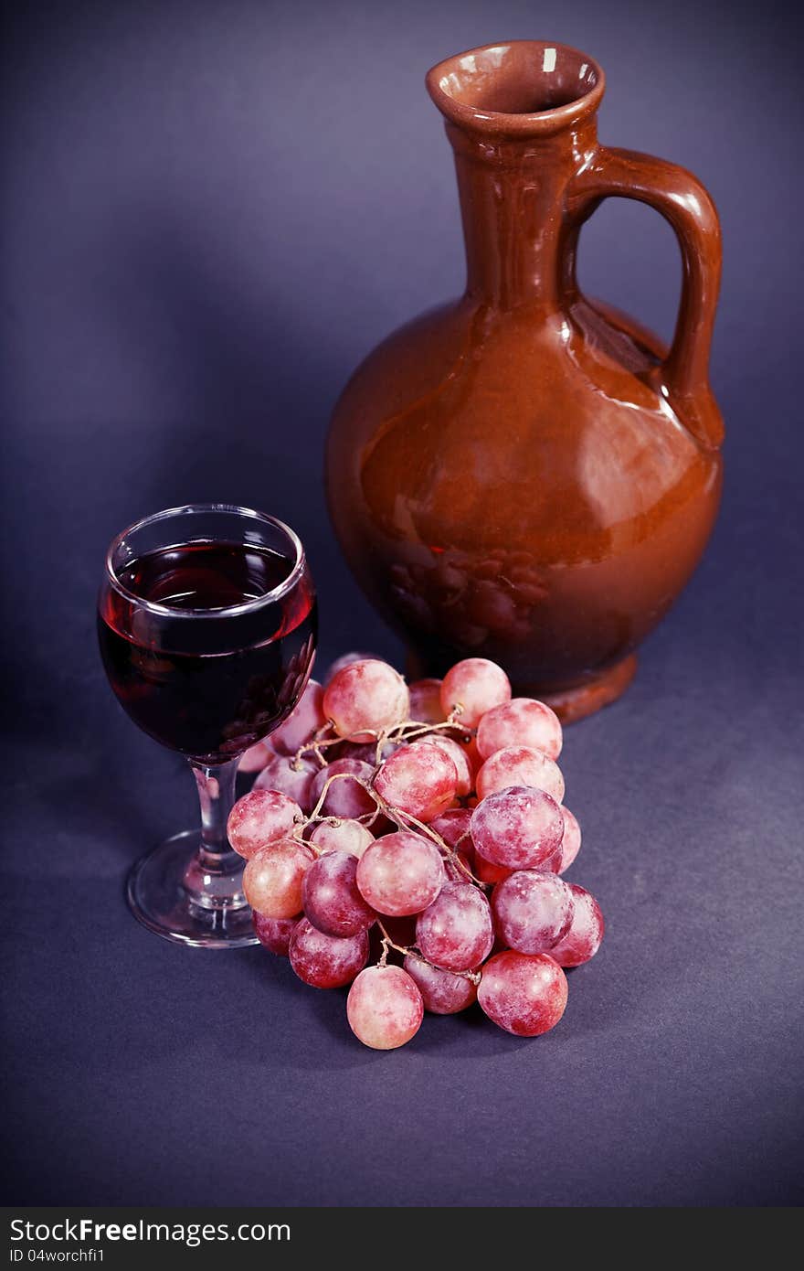 Glass and a jug of red wine on a dark background