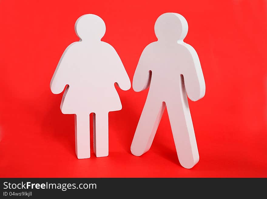 Male and female wooden figures on a red background. Male and female wooden figures on a red background