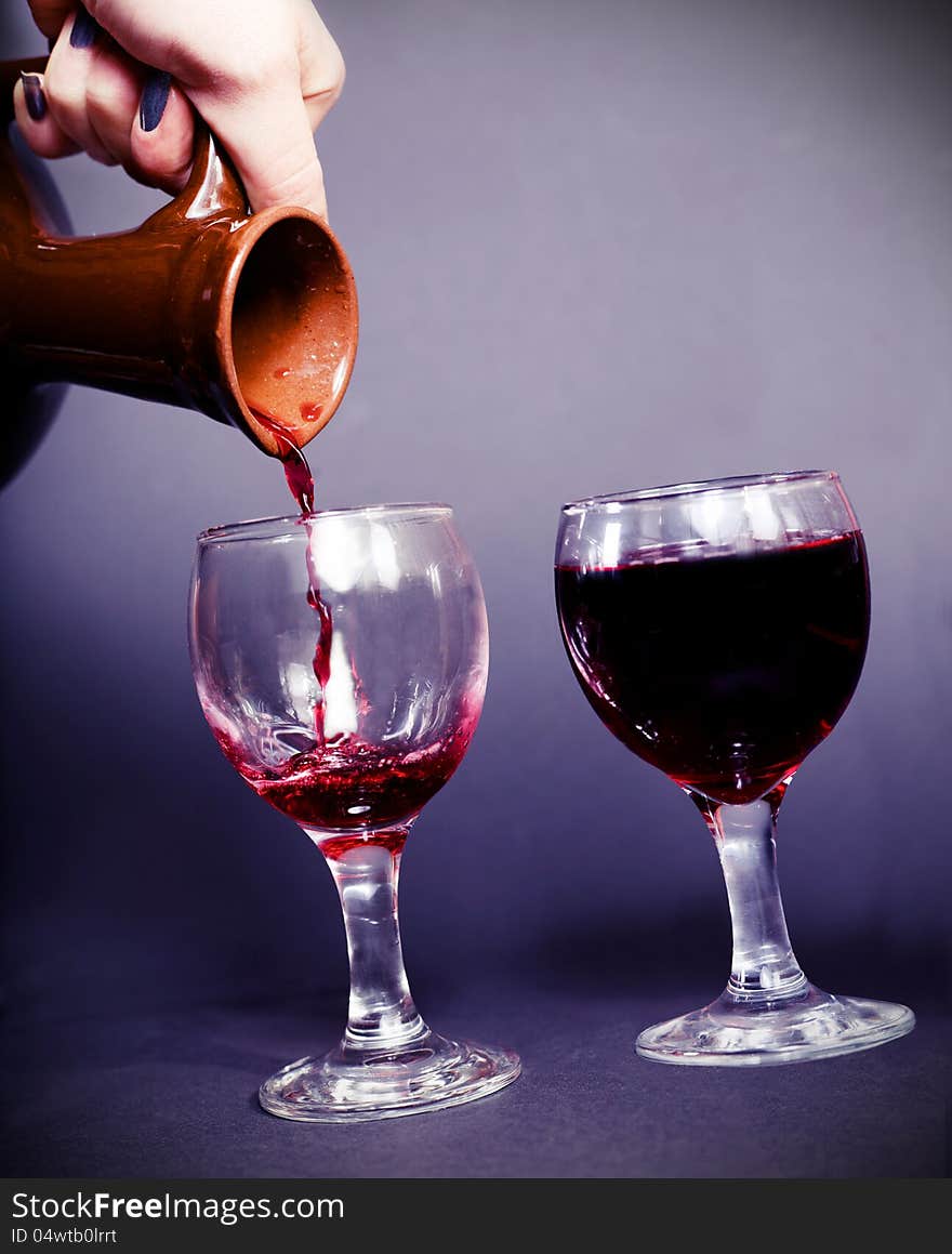 Pouring wine from an ancient pitcher dark background