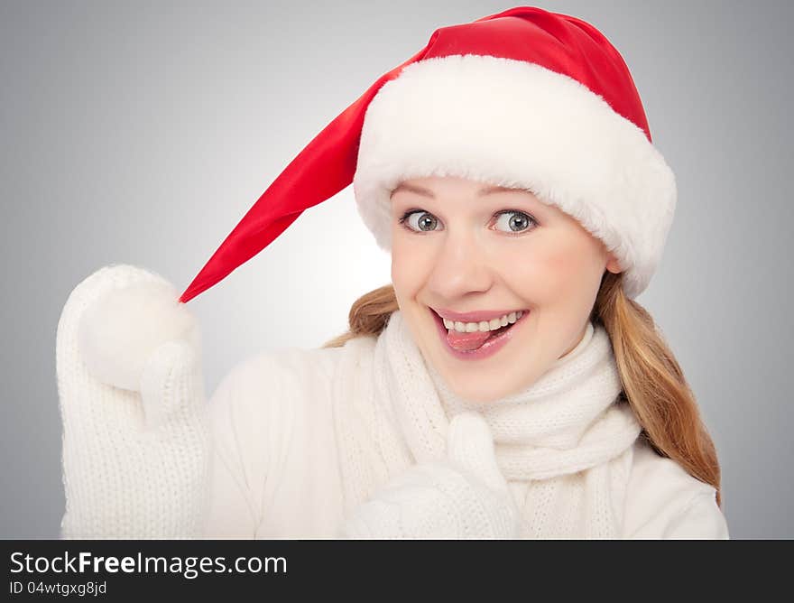 Happy funny girl in a Christmas hat show tongue on gray background