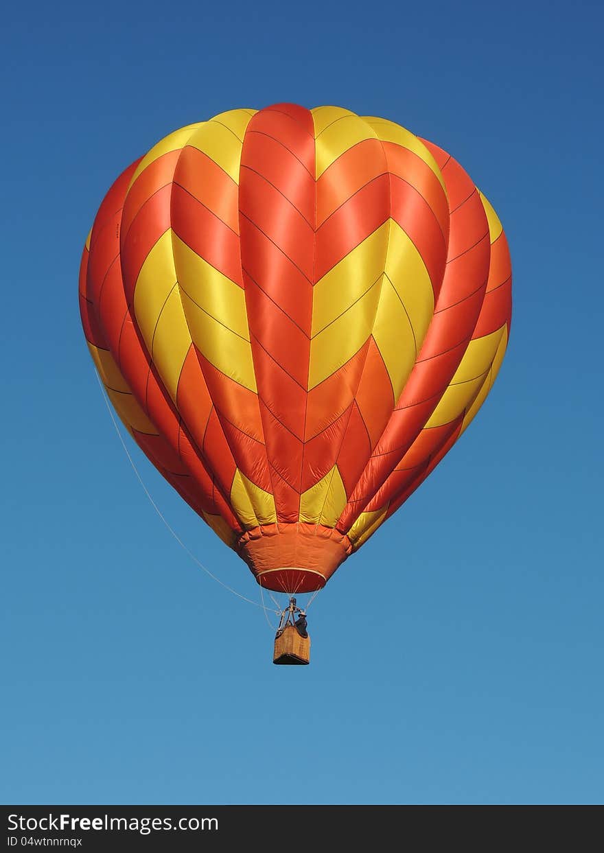 Notice the incredible artistry, obvious in this close-up, in the choice of colors and patterns used in the intricate fabric work of this hot air balloon just lifting off. It glimmers in the sun floating in blue sky. Notice the incredible artistry, obvious in this close-up, in the choice of colors and patterns used in the intricate fabric work of this hot air balloon just lifting off. It glimmers in the sun floating in blue sky.