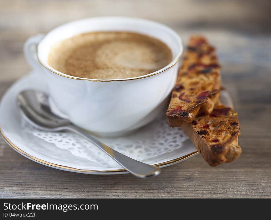 A cup of coffee and biscotti on a wooden table. A cup of coffee and biscotti on a wooden table