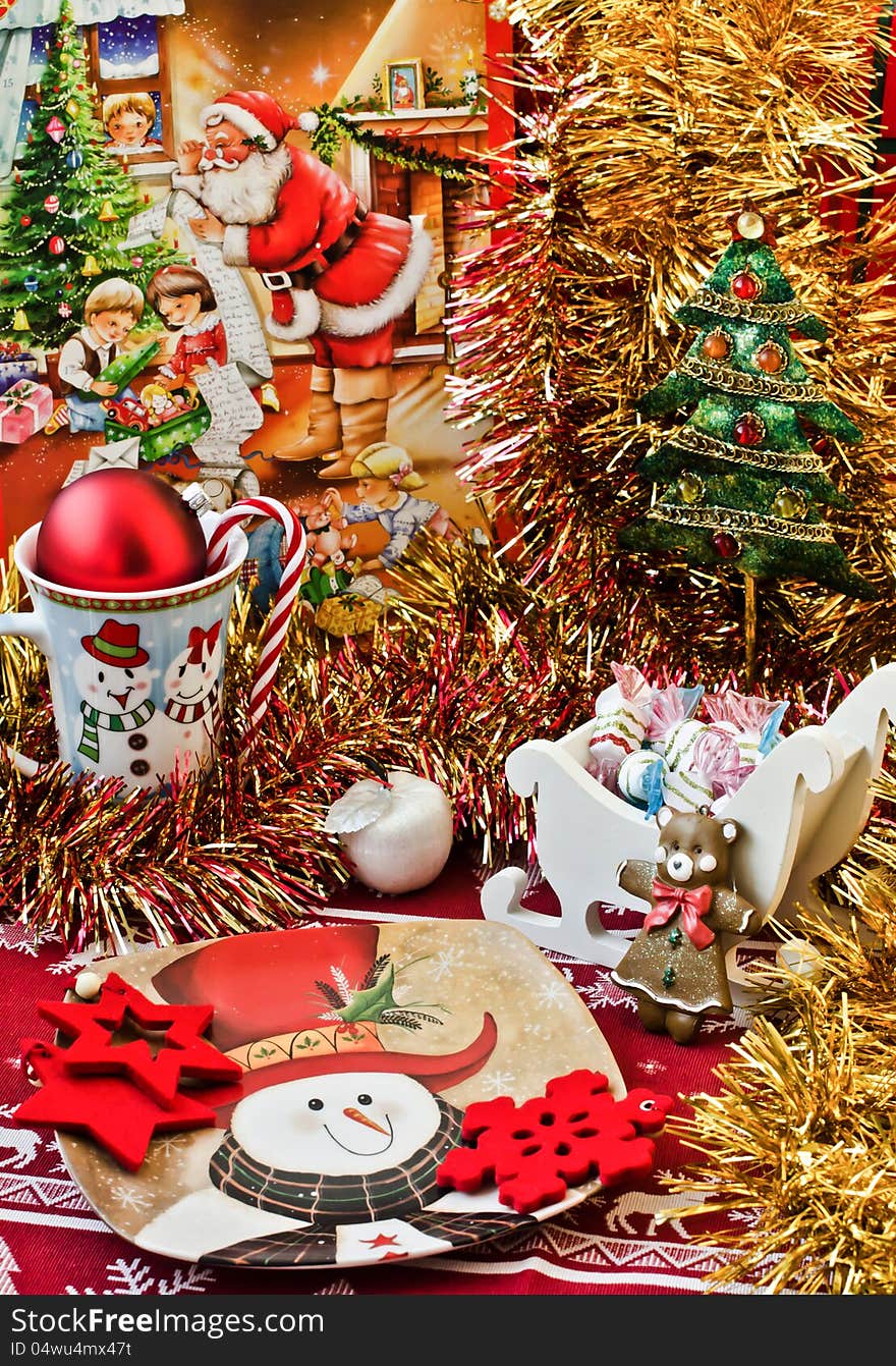 Christmas table arrangement with golden tinsel. Snowman cup and plate.