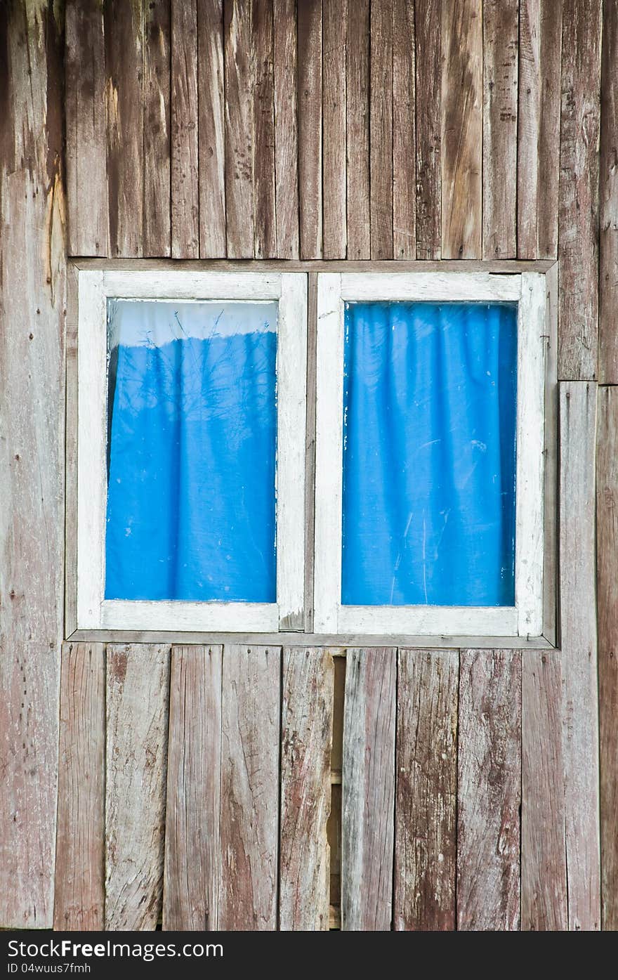 A window that have white frame and blue curtain