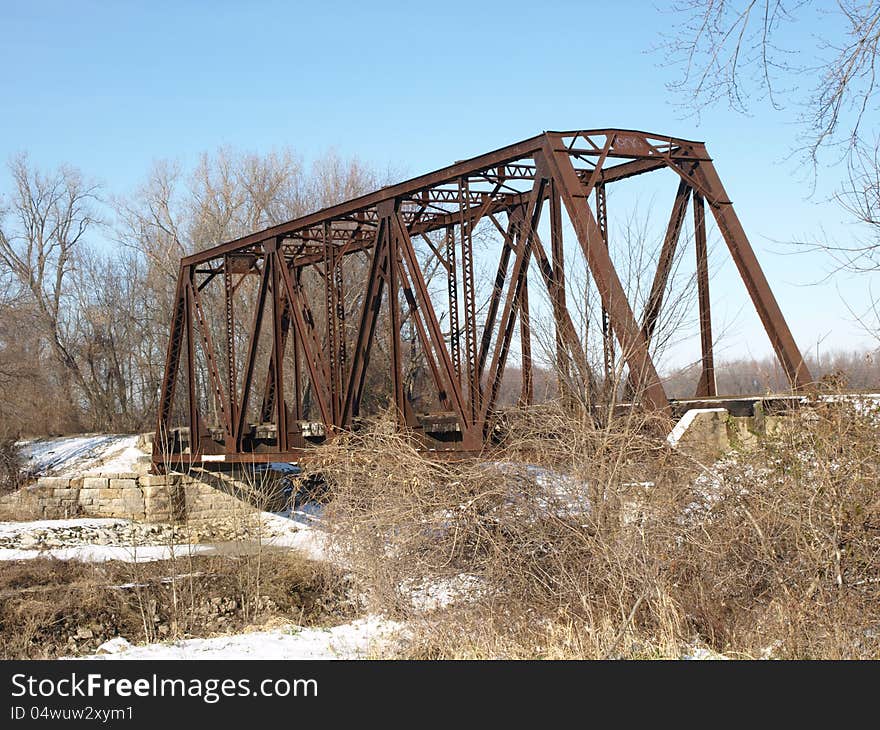 A rusted railway bridge in a snowy winter scene