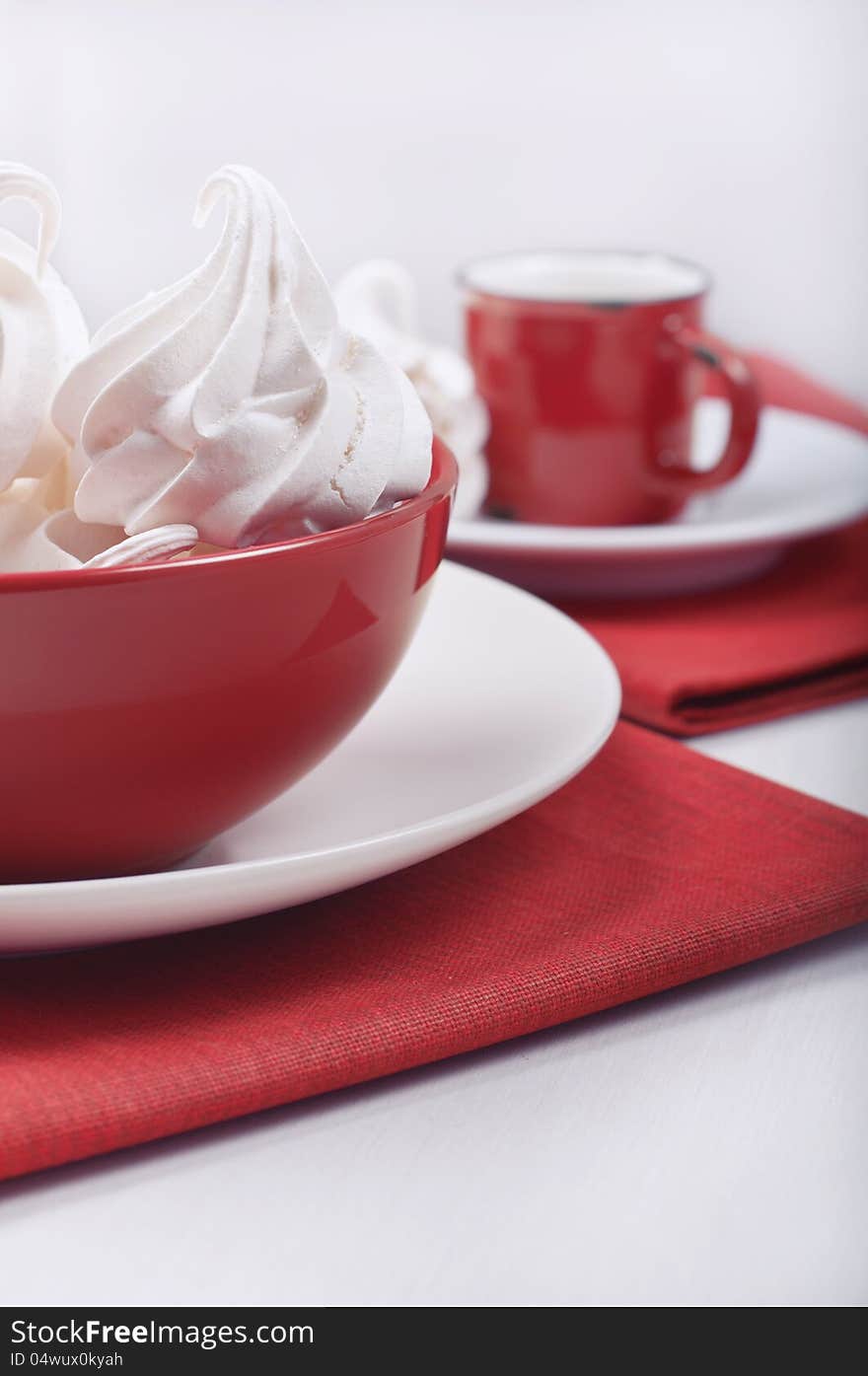 Closeup side view of a red bowl with meringues and away the red cup on the red rag towels. Closeup side view of a red bowl with meringues and away the red cup on the red rag towels.