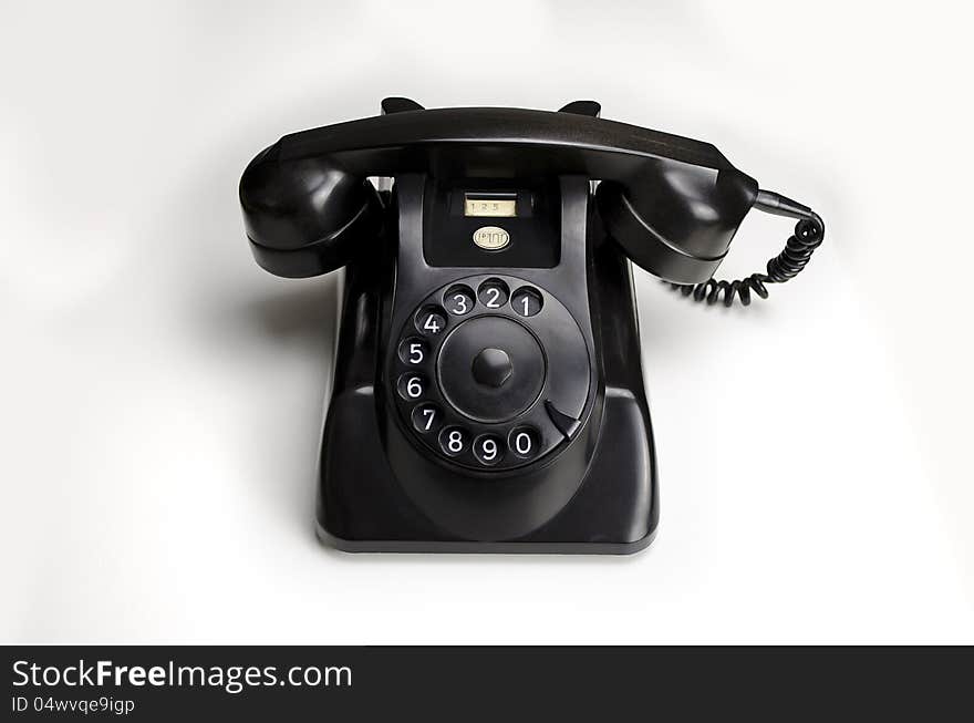 Old black Bakelite telephone (Type 1955 by PTT/HEEMAF) with rotary dial, on white background. Old black Bakelite telephone (Type 1955 by PTT/HEEMAF) with rotary dial, on white background.