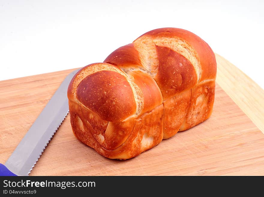 Loaf of bread is dark gray on a wooden board next to the knife. Loaf of bread is dark gray on a wooden board next to the knife