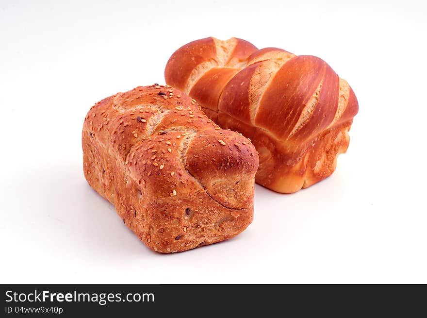 Two rolls of white and dark bread lie against a white background. Two rolls of white and dark bread lie against a white background