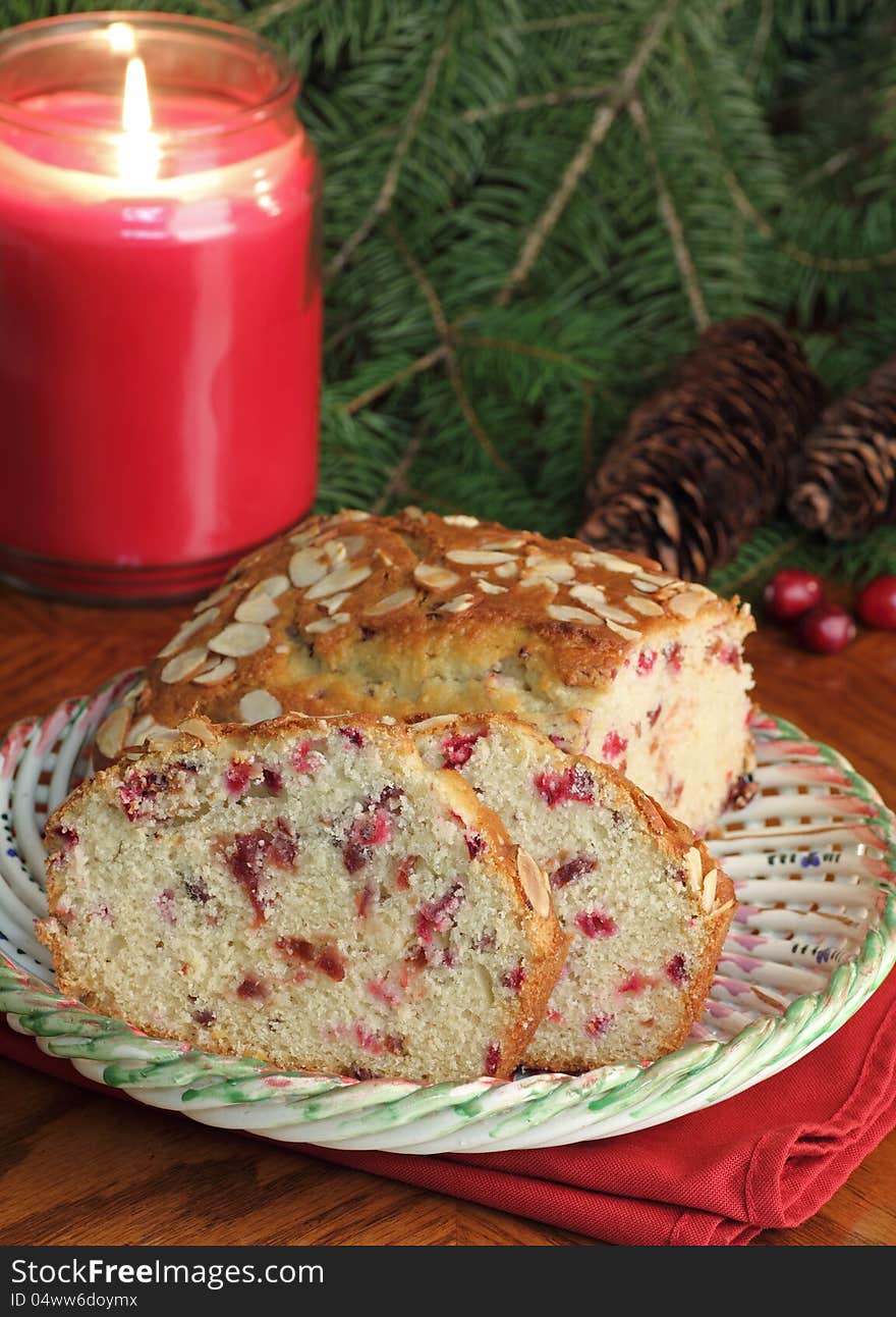 Sliced cranberry bread on a plate with candle burning in background. Sliced cranberry bread on a plate with candle burning in background