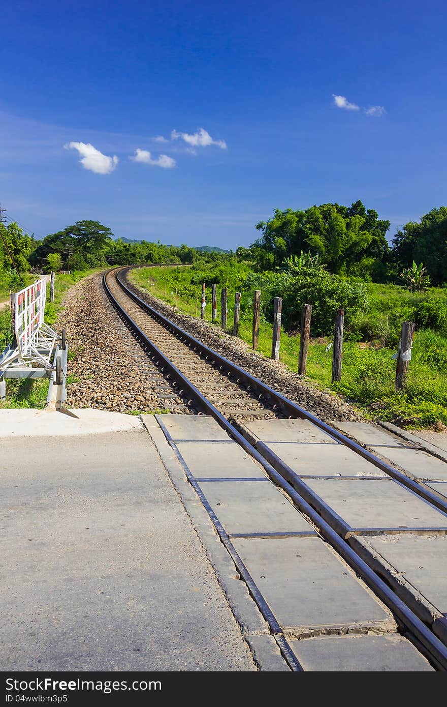 Curve railway track cross the road with mountain background