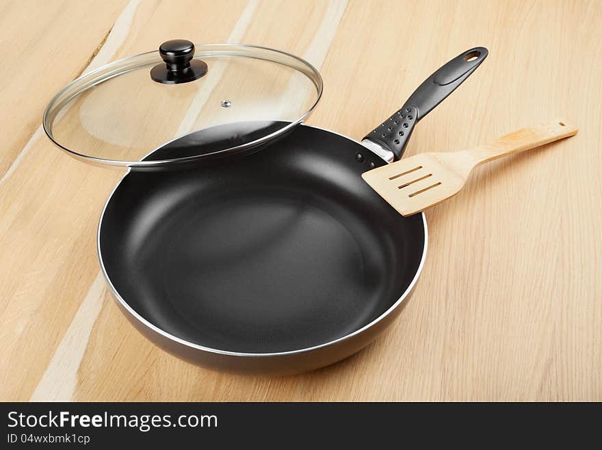 Frying pan with lid on wooden table. Frying pan with lid on wooden table