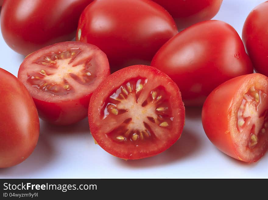 A group a tomatoes and some sliced tomatoes in front. A group a tomatoes and some sliced tomatoes in front