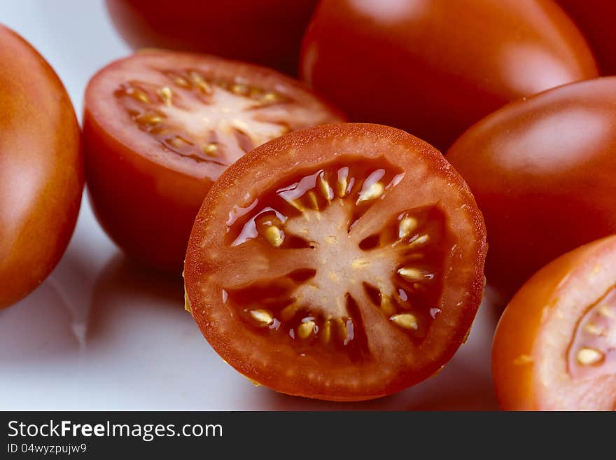 A group a tomatoes and some sliced tomatoes in front