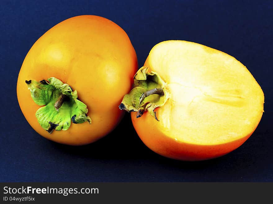 Portrait photo of a full and a half piece of sharon fruit. Portrait photo of a full and a half piece of sharon fruit