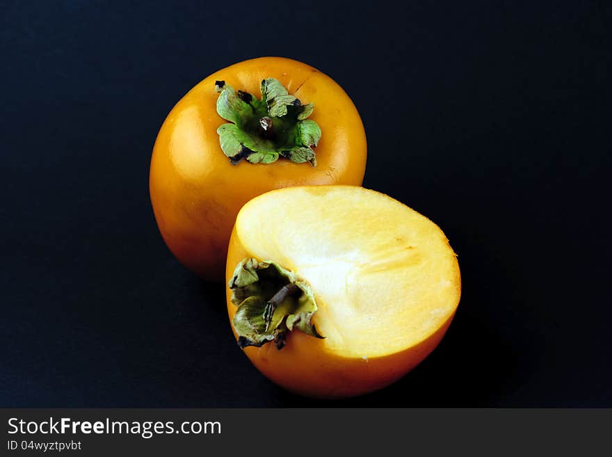 Portrait photo of a full and a half piece of sharon fruit. Portrait photo of a full and a half piece of sharon fruit