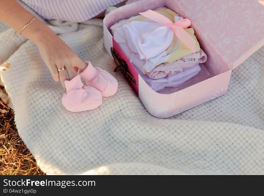 Pretty pregnant woman with childrens clothes at home. Pretty pregnant woman with childrens clothes at home