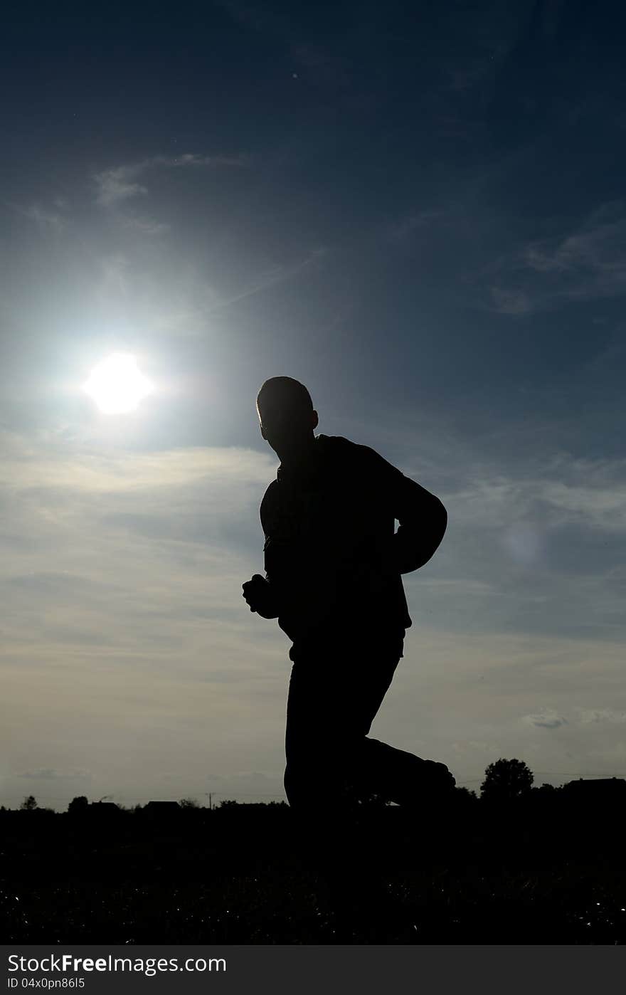 Figure of jogging runner. One person running in strong sun, unclear face. Figure of jogging runner. One person running in strong sun, unclear face.