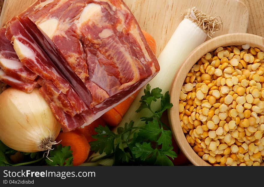 Ingredients of Pea Soup with Yellow Pea, Onion, Leek, Carrot, Parsley and Smoked Ham on Wooden Cutting Board closeup. Ingredients of Pea Soup with Yellow Pea, Onion, Leek, Carrot, Parsley and Smoked Ham on Wooden Cutting Board closeup