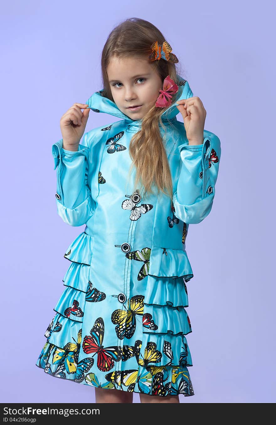 Portrait of a cute little girl in a beautiful colored coat with butterflies posing in studio. Portrait of a cute little girl in a beautiful colored coat with butterflies posing in studio