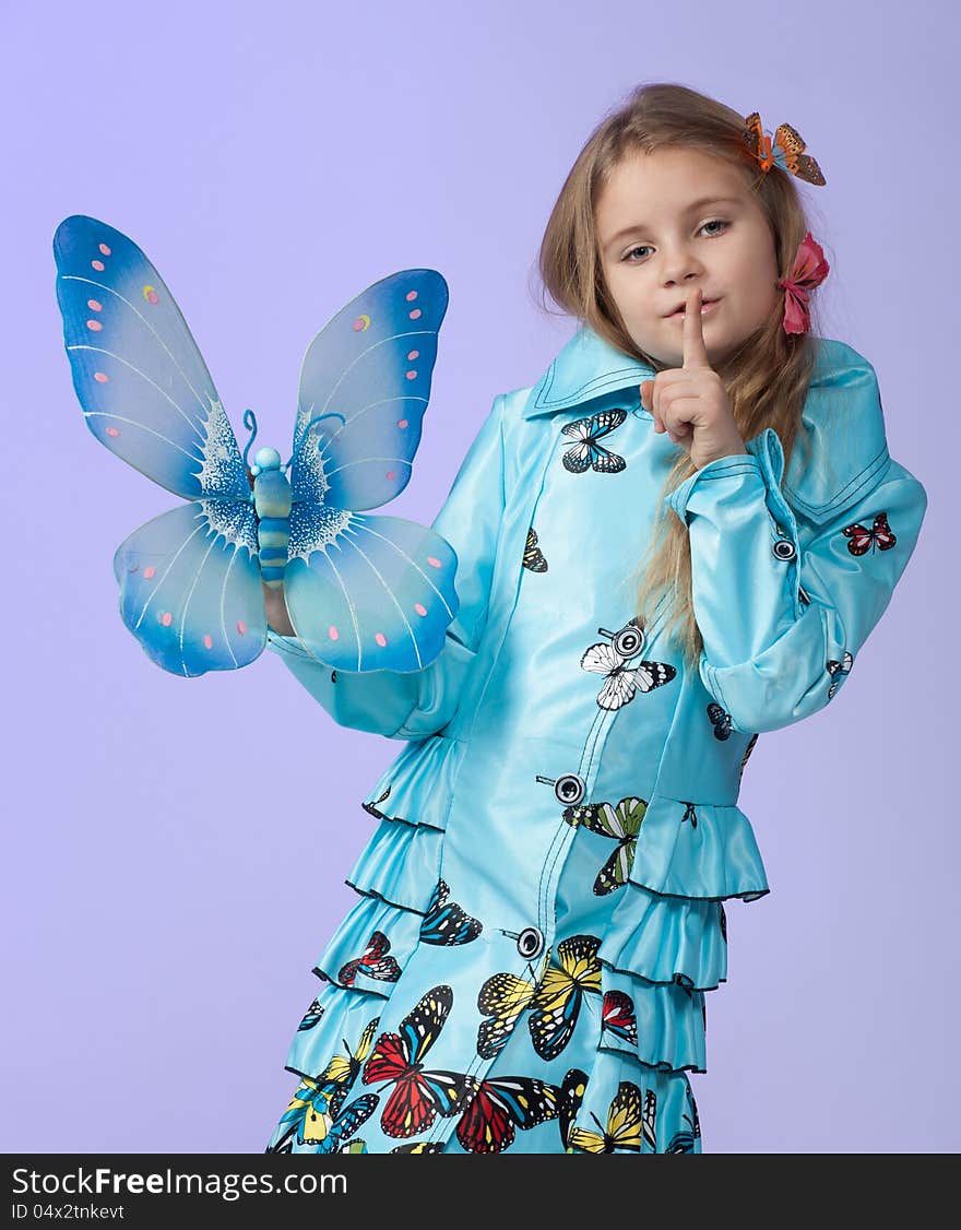 Portrait of a cute little girl in a beautiful colored coat with butterflies posing in studio. Portrait of a cute little girl in a beautiful colored coat with butterflies posing in studio