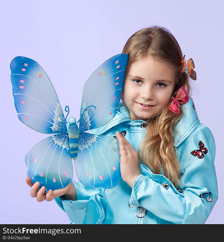 Portrait of a cute little girl in a beautiful colored coat with butterflies posing in studio. Portrait of a cute little girl in a beautiful colored coat with butterflies posing in studio