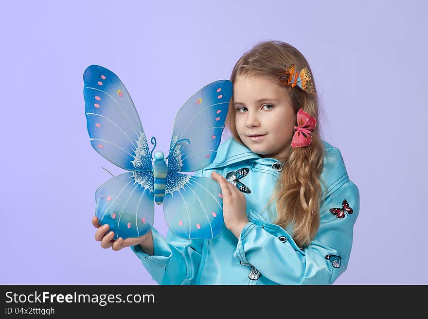 Portrait of a cute little girl in a beautiful colored coat with butterflies posing in studio. Portrait of a cute little girl in a beautiful colored coat with butterflies posing in studio