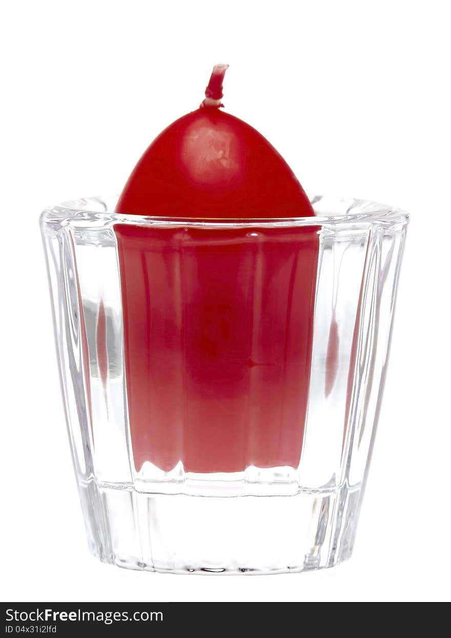 Candlestick in the form of a glass from the transparent glass. Glass walls thick, cut. The candle is inserted into a candlestick. The candle has the egg form. Candle of red color. Isolated on white. Candlestick in the form of a glass from the transparent glass. Glass walls thick, cut. The candle is inserted into a candlestick. The candle has the egg form. Candle of red color. Isolated on white.