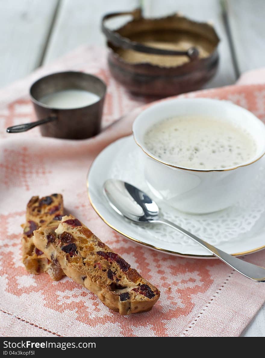 A cup of coffee and biscotti on a wooden table. A cup of coffee and biscotti on a wooden table