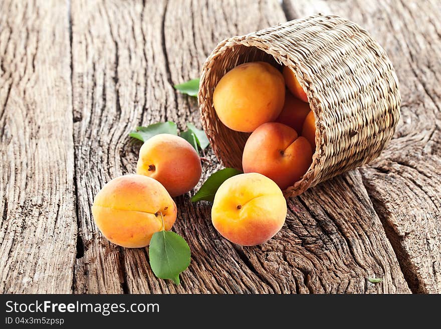 Apricots with leaves on the old wooden table.