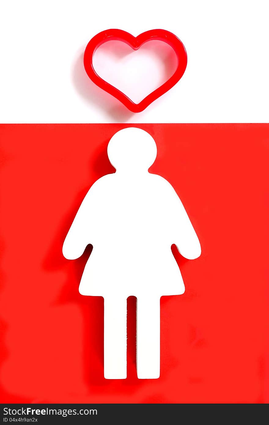 Wooden female figure on a red background with a big red heart on her. Wooden female figure on a red background with a big red heart on her