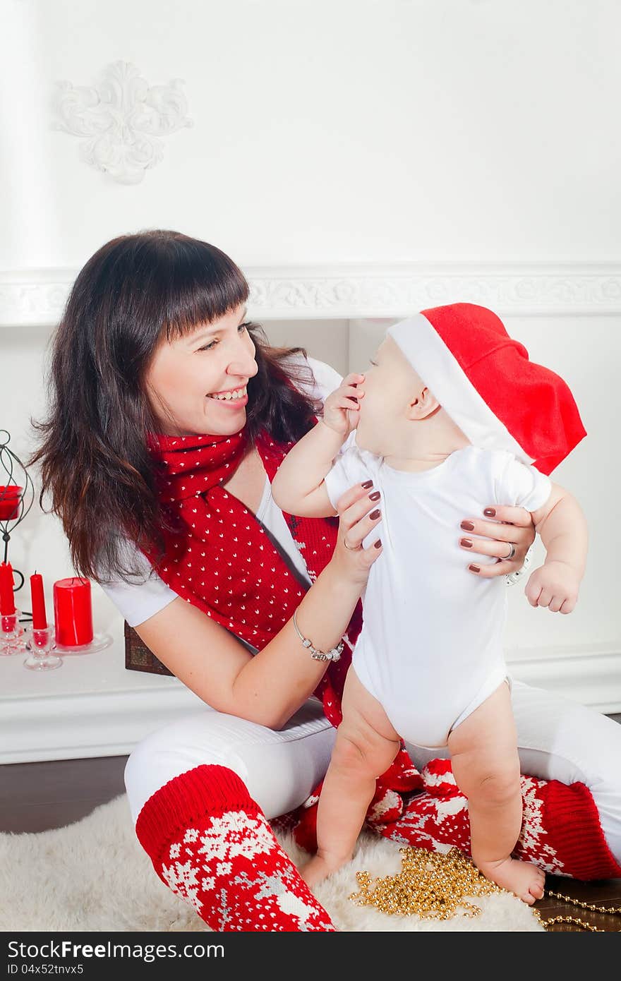 Young mother holding her little son, it is Christmas time, the boy wearing Santa's hat, they are laughing. Young mother holding her little son, it is Christmas time, the boy wearing Santa's hat, they are laughing