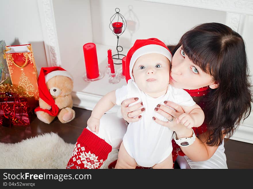 Young mother kissing her little son, the boy is in Santa's cap. Young mother kissing her little son, the boy is in Santa's cap