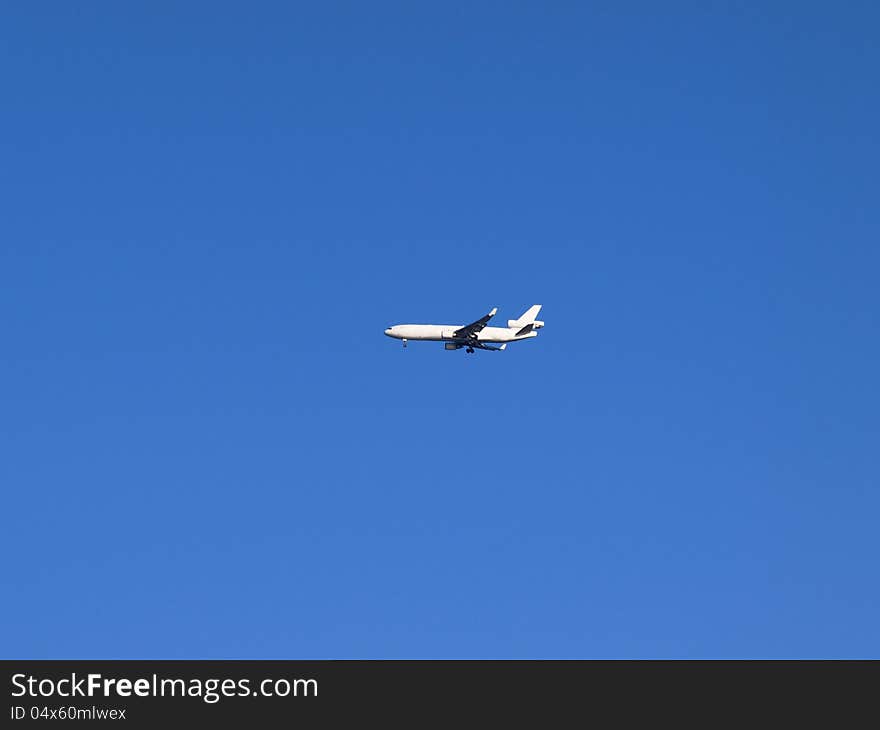 White airplane in the blue sky, coming in for landing